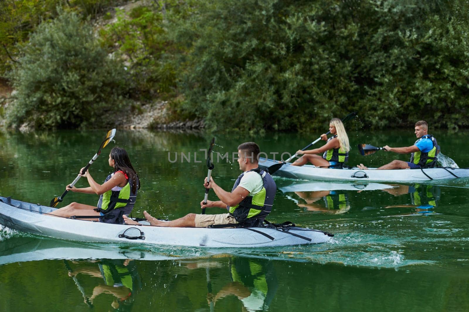 A group of friends enjoying having fun and kayaking while exploring the calm river, surrounding forest and large natural river canyons by dotshock