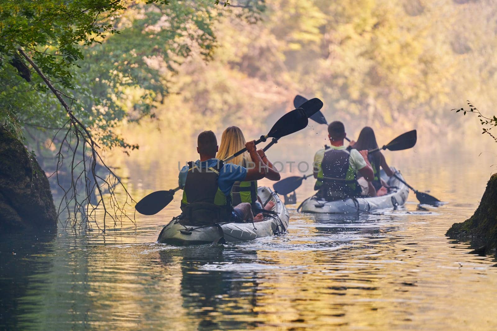 A group of friends enjoying having fun and kayaking while exploring the calm river, surrounding forest and large natural river canyons by dotshock