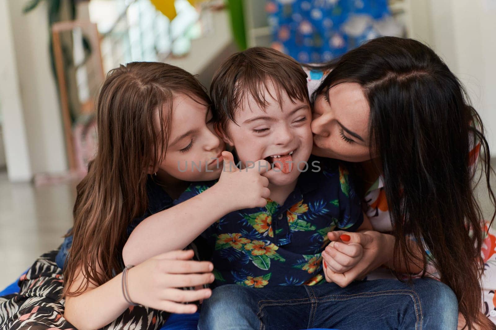 A girl and a woman hug a child with down syndrome in a modern preschool institution. High quality photo