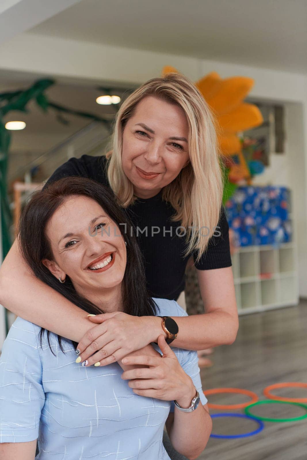 Two women share a heartfelt embrace while at a preschool, showcasing the nurturing and supportive environment for learning and growth by dotshock