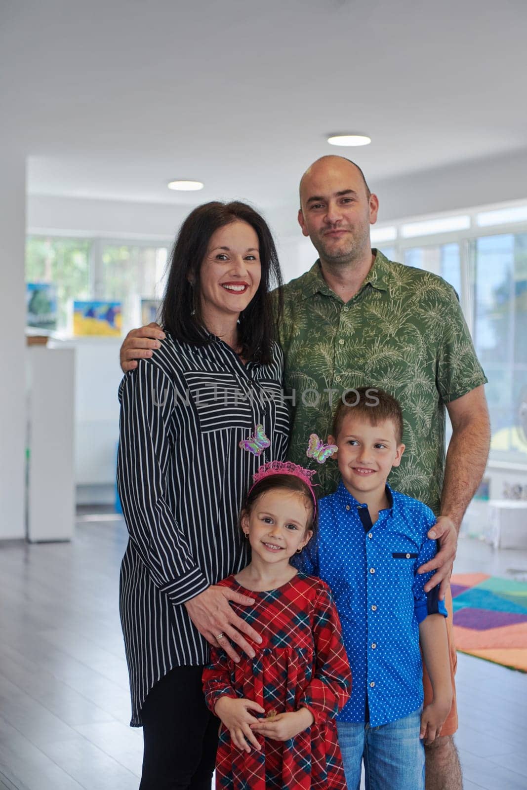 Portrait of a happy family. Photo of parents with children in a modern preschool classroom. Selective focus by dotshock