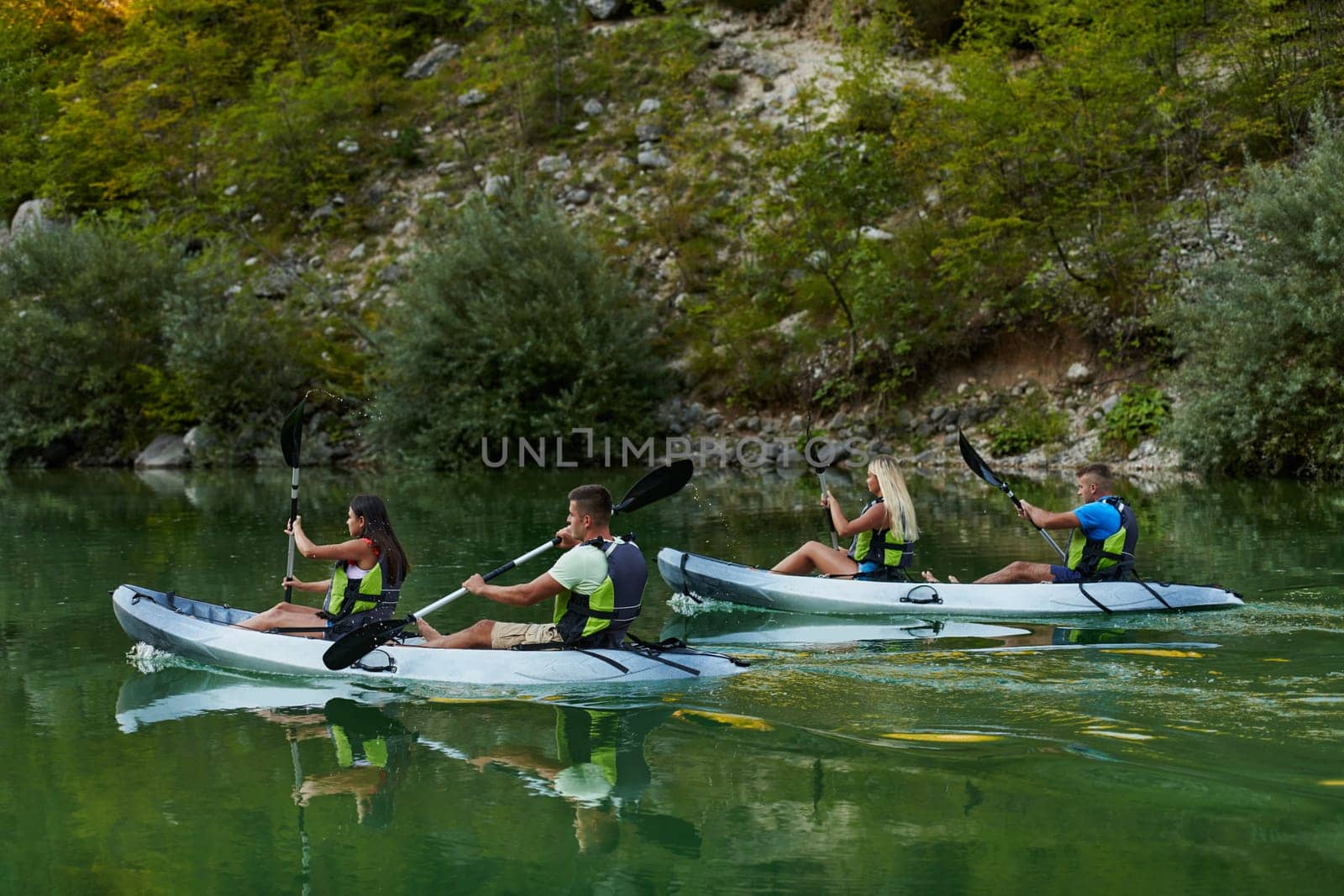 A group of friends enjoying having fun and kayaking while exploring the calm river, surrounding forest and large natural river canyons.