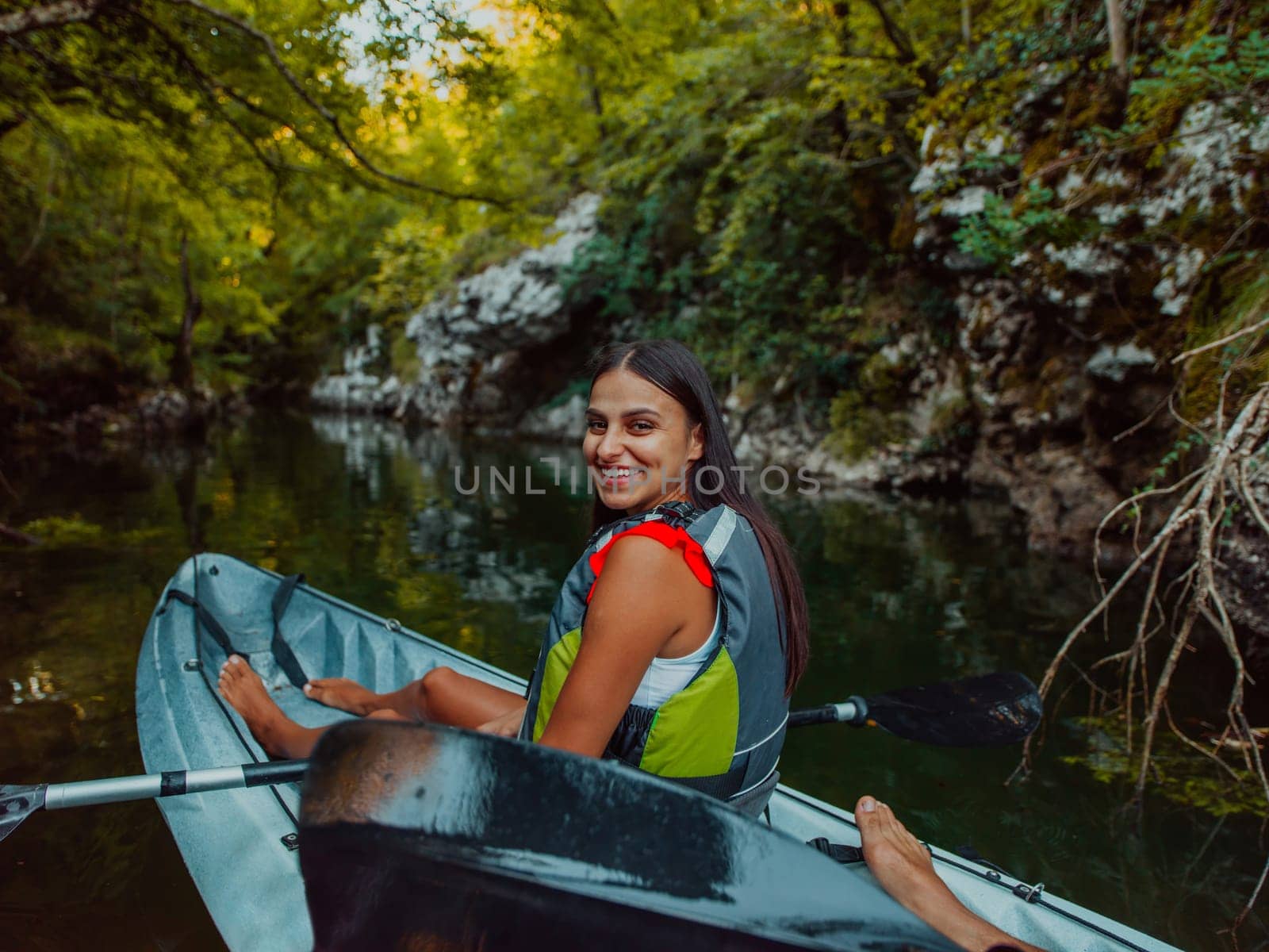 A smiling woman enjoying a relaxing kayak ride with a friend while exploring river canyons by dotshock