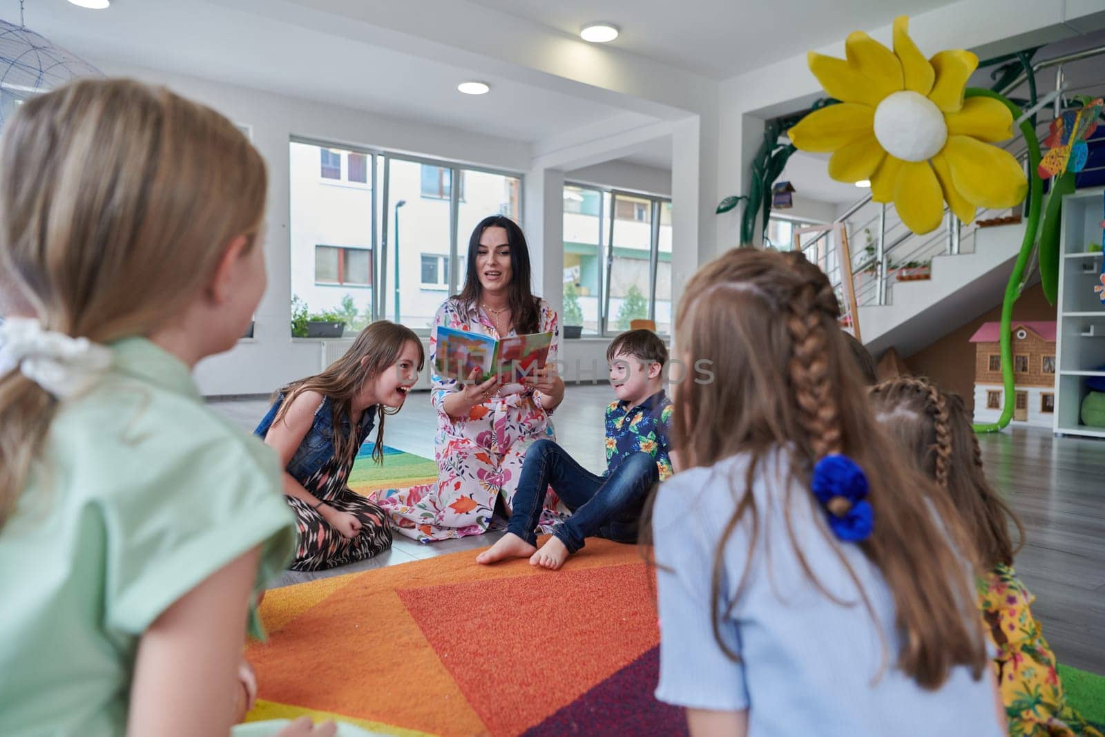 Reading time in an elementary school or kindergarten, a teacher reading a book to children in an elementary school or kindergarten. The concept of pre-school education. Selective focus by dotshock