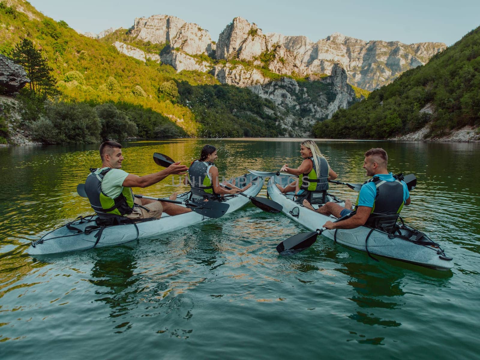 A group of friends enjoying having fun and kayaking while exploring the calm river, surrounding forest and large natural river canyons.