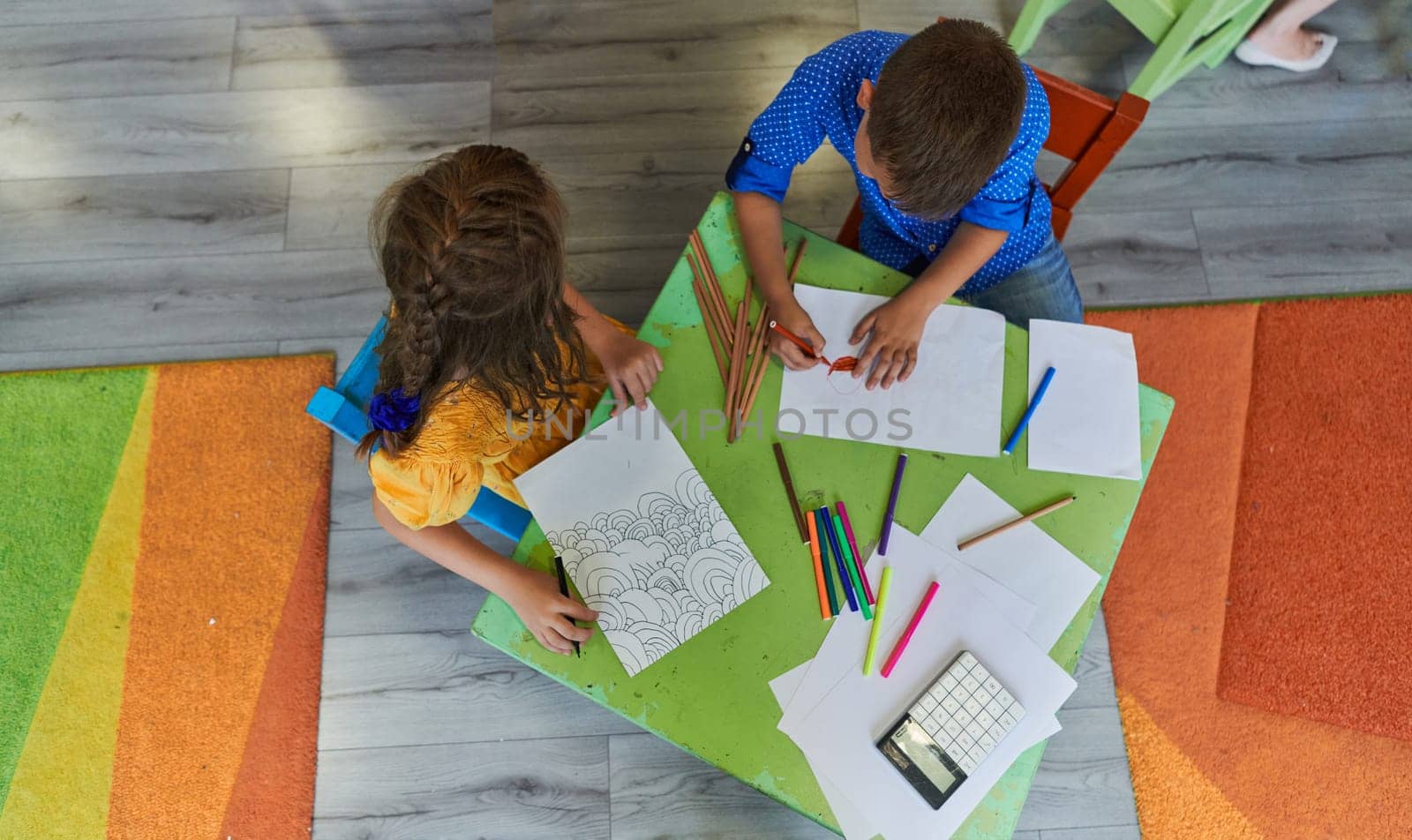 Cute girl and boy sit and draw together in preschool institution. High quality photo