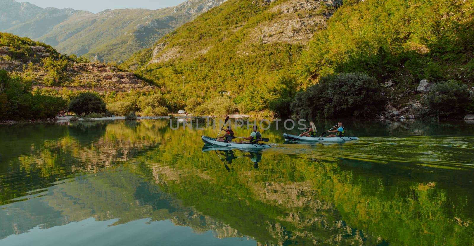 A group of friends enjoying having fun and kayaking while exploring the calm river, surrounding forest and large natural river canyons by dotshock