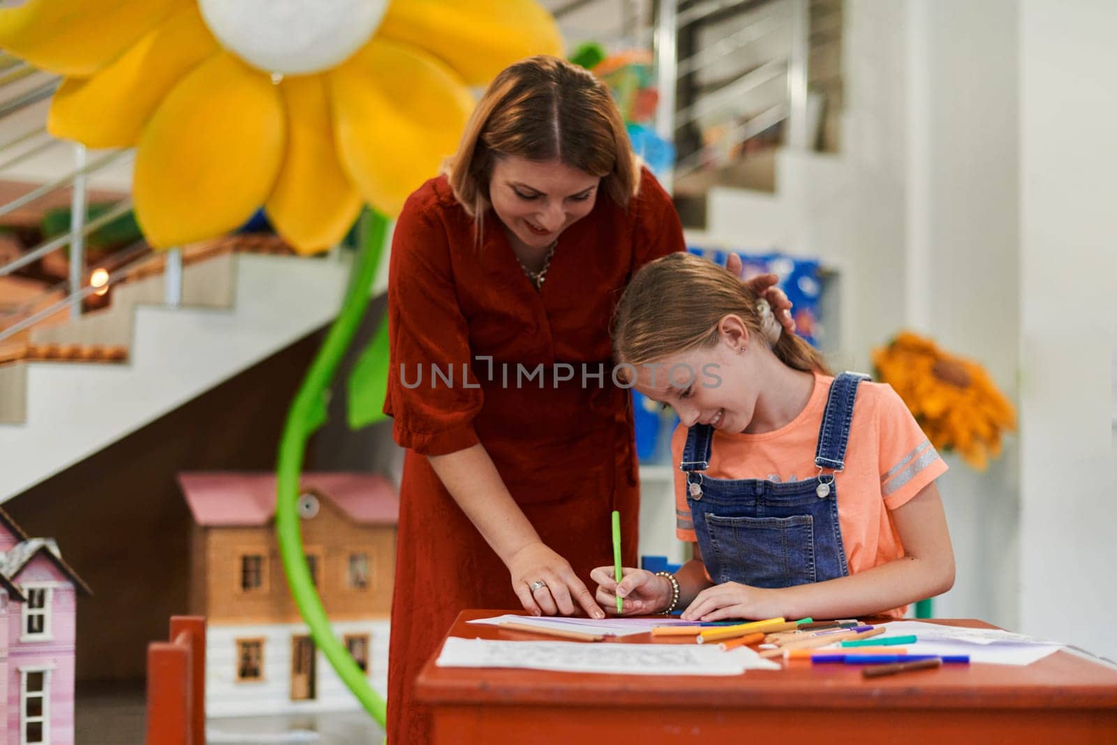 Creative kids during an art class in a daycare center or elementary school classroom drawing with female teacher. High quality photo