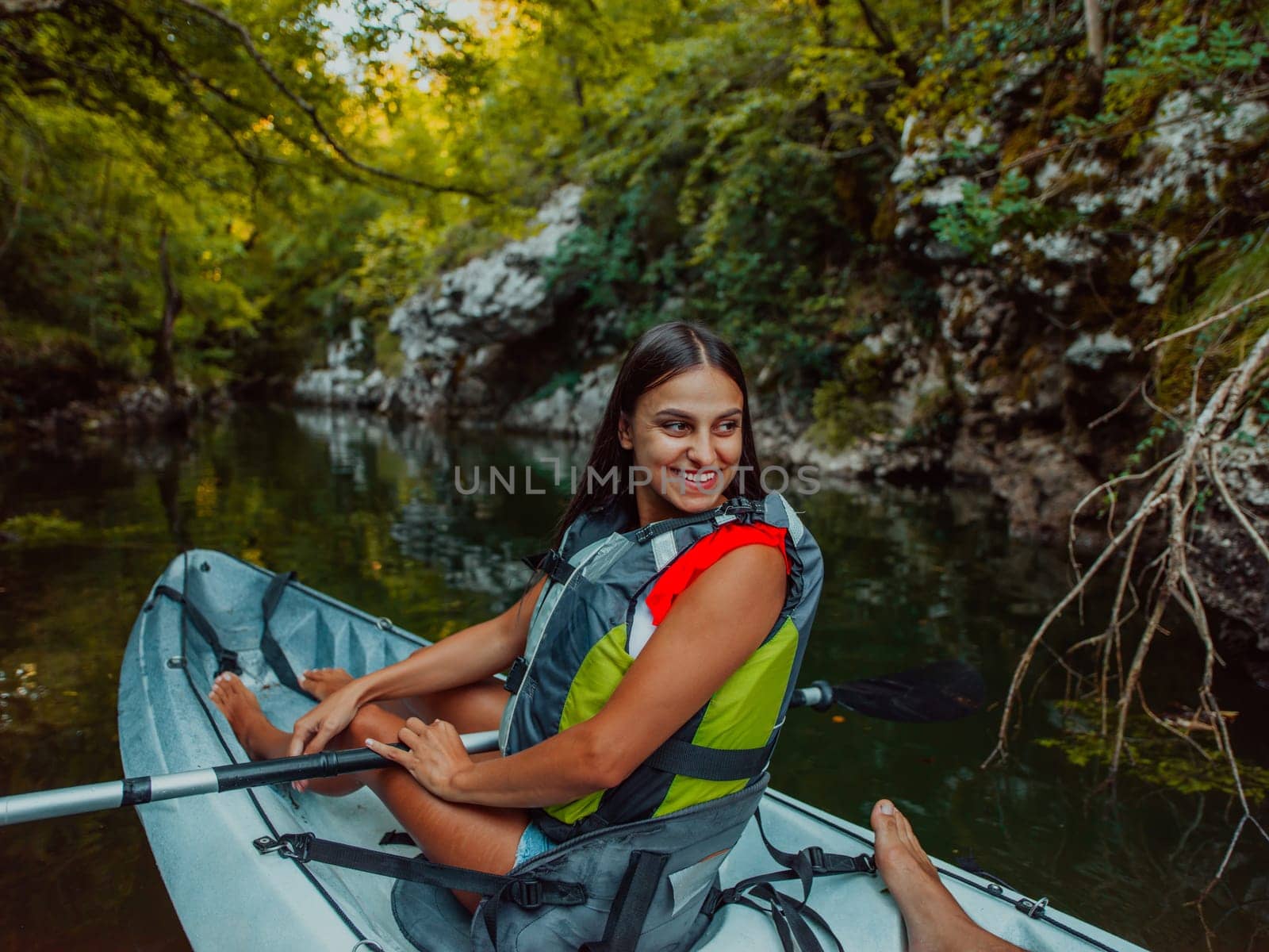 A smiling woman enjoying a relaxing kayak ride with a friend while exploring river canyons by dotshock