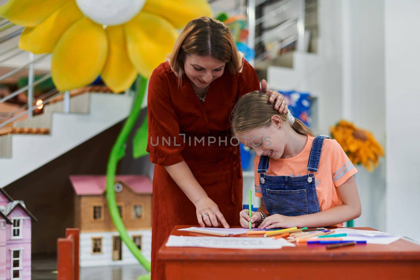 Creative kids during an art class in a daycare center or elementary school classroom drawing with female teacher. by dotshock