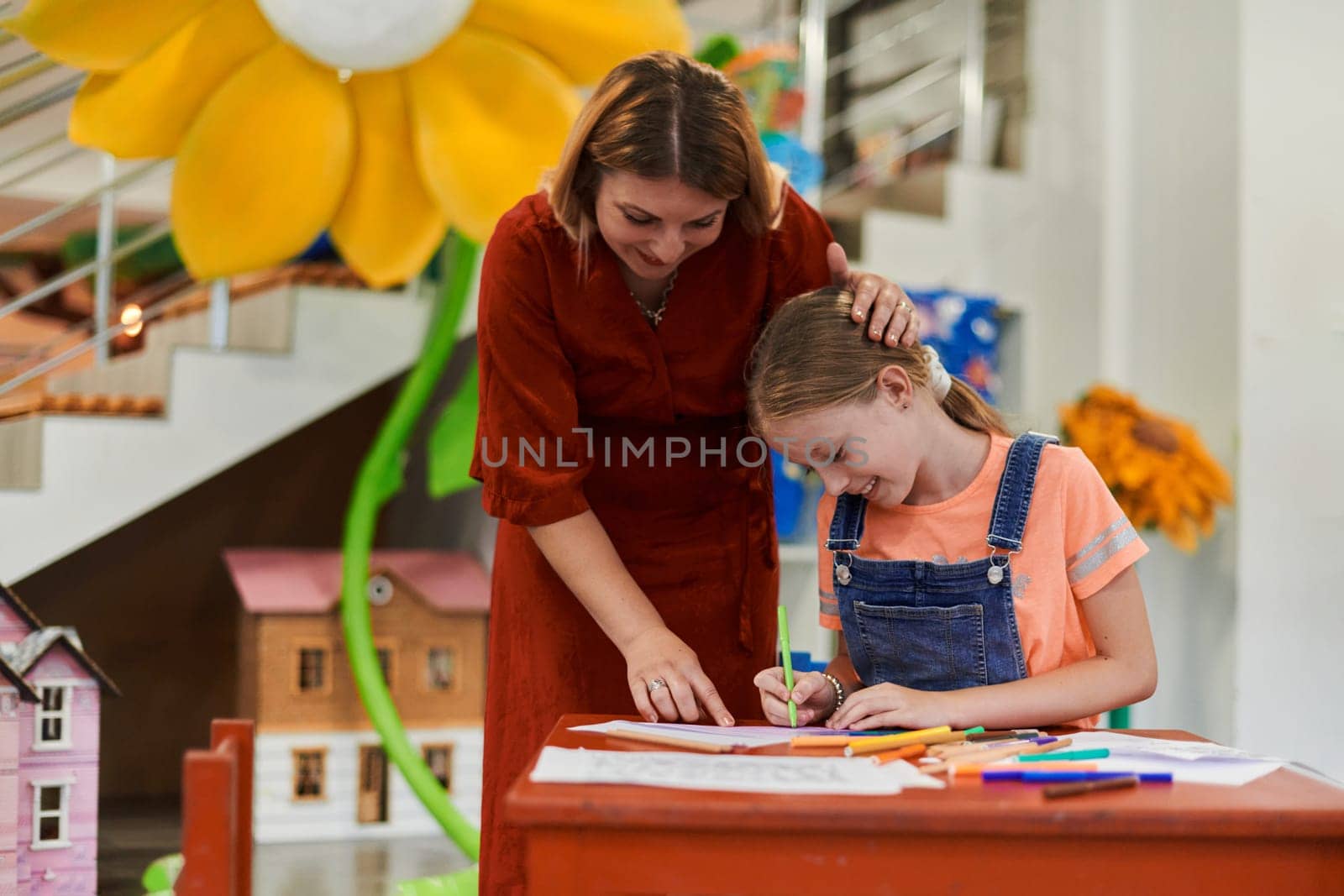 Creative kids during an art class in a daycare center or elementary school classroom drawing with female teacher. High quality photo