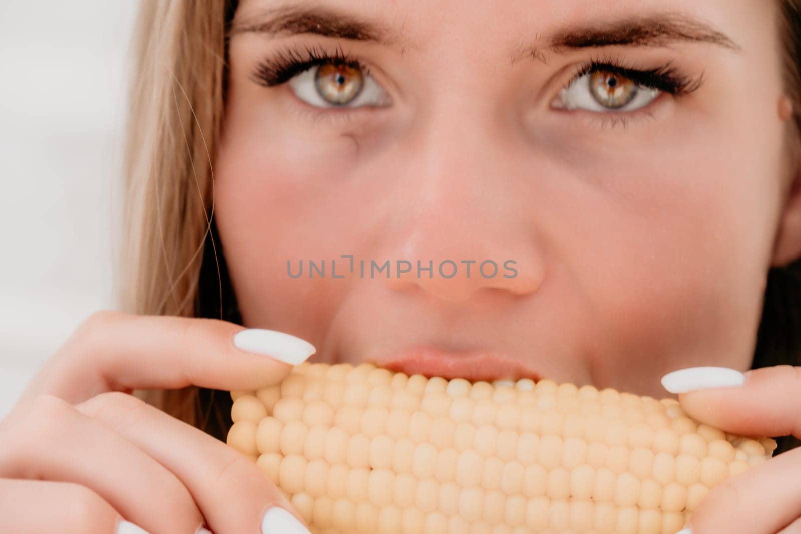 Woman eats corn on beach. Vegetarian hipster woman eat fresh organic grilled corn. Happy lady on sea beach sunset or ocean sunrise. Travel, explore, active yoga and meditation lifestyle concept. by panophotograph