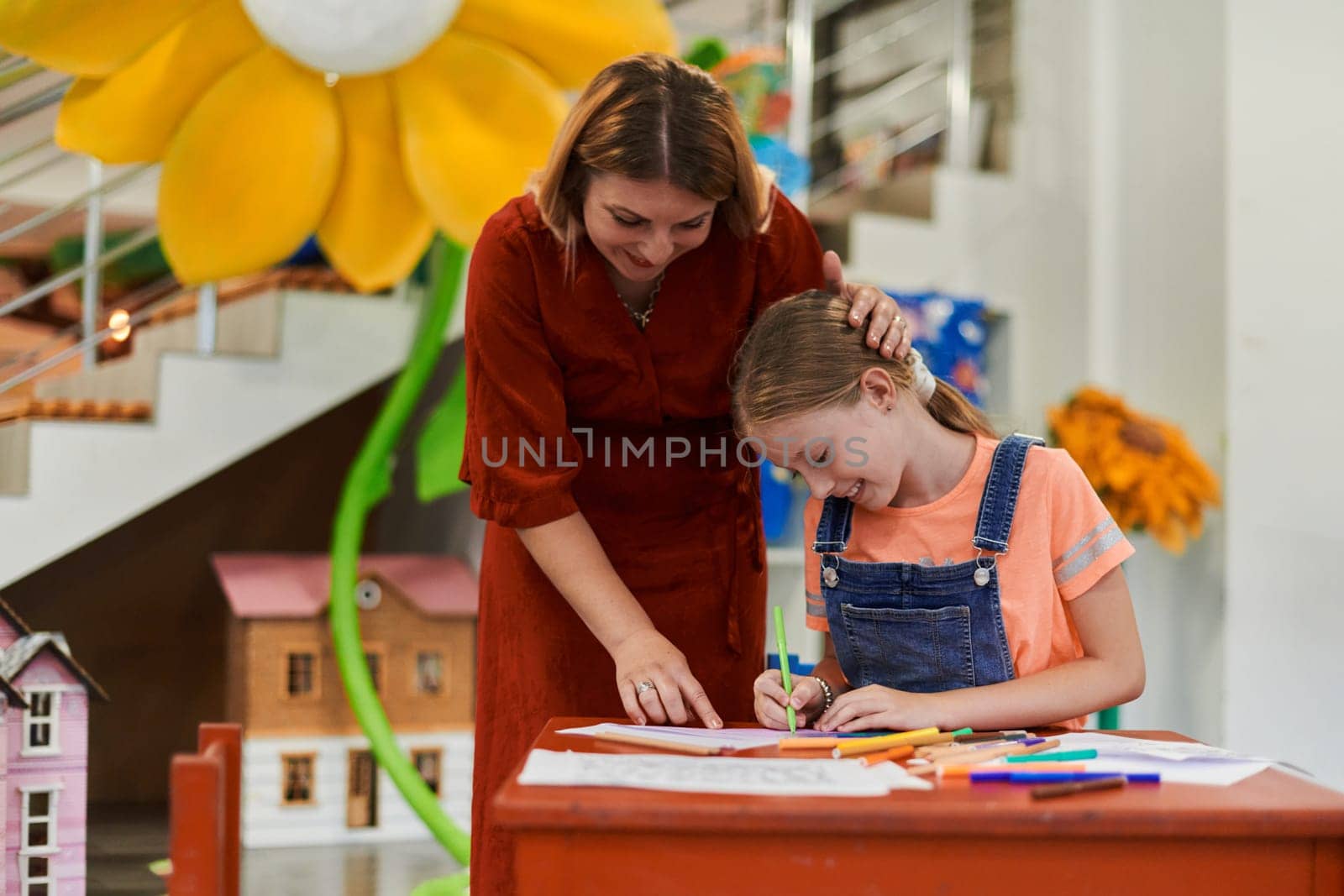 Creative kids during an art class in a daycare center or elementary school classroom drawing with female teacher. by dotshock