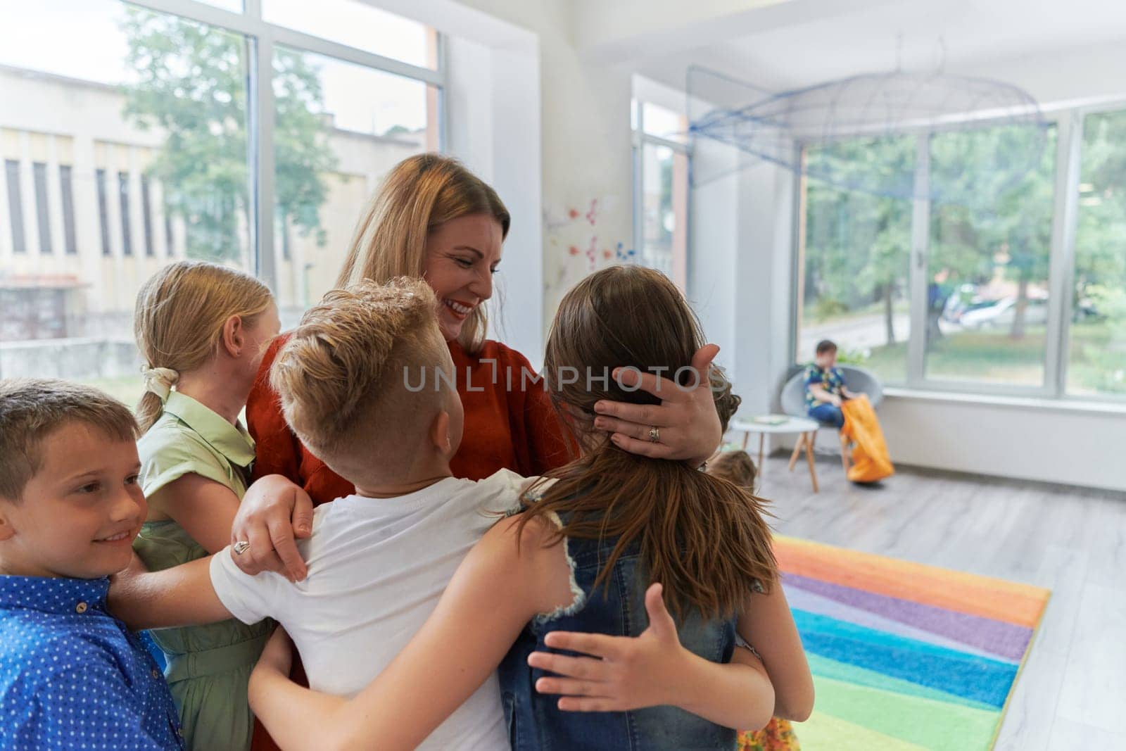 A child hugging a teacher in a modern kindergarten. High quality photo