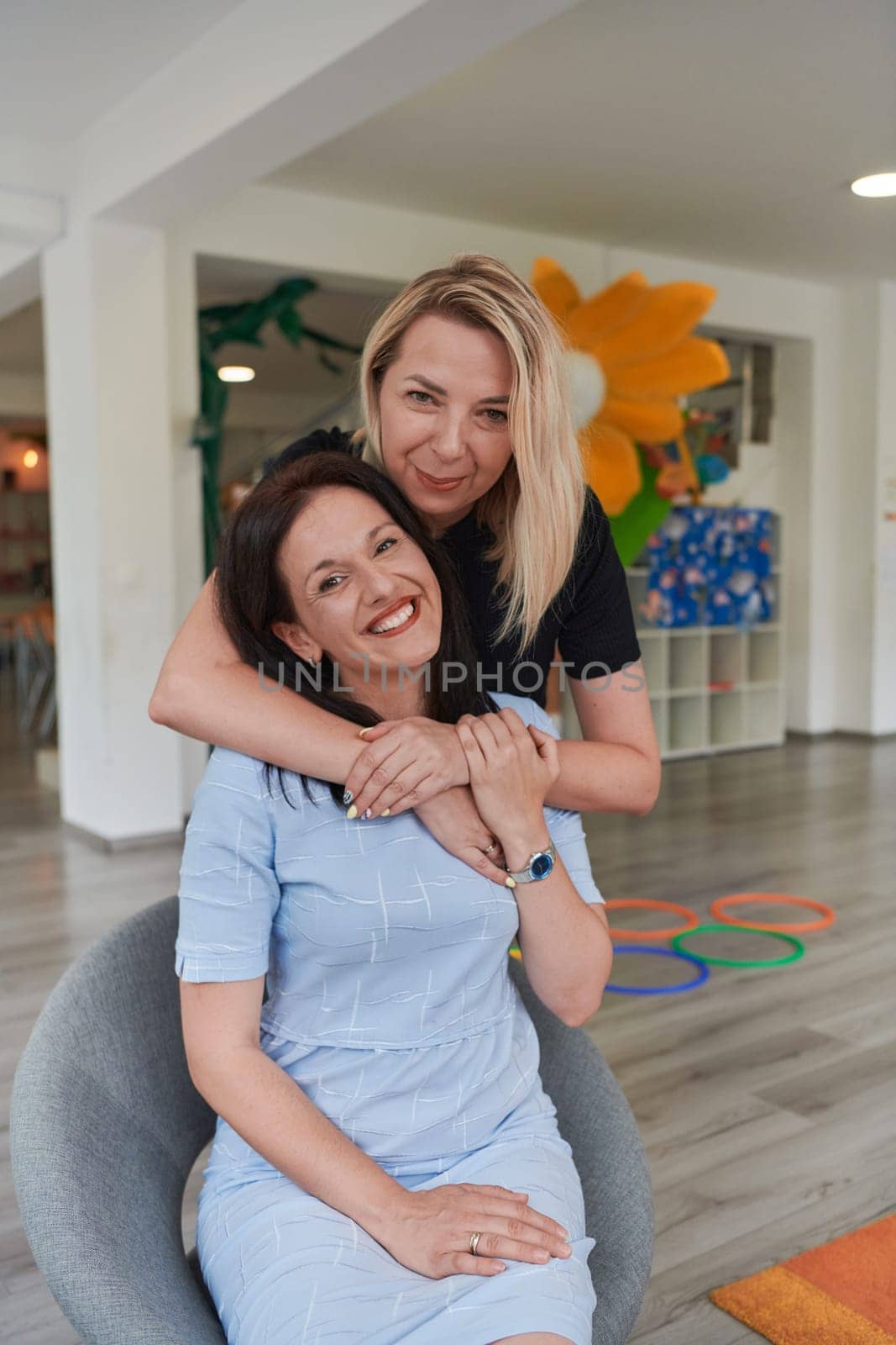 Two women share a heartfelt embrace while at a preschool, showcasing the nurturing and supportive environment for learning and growth by dotshock