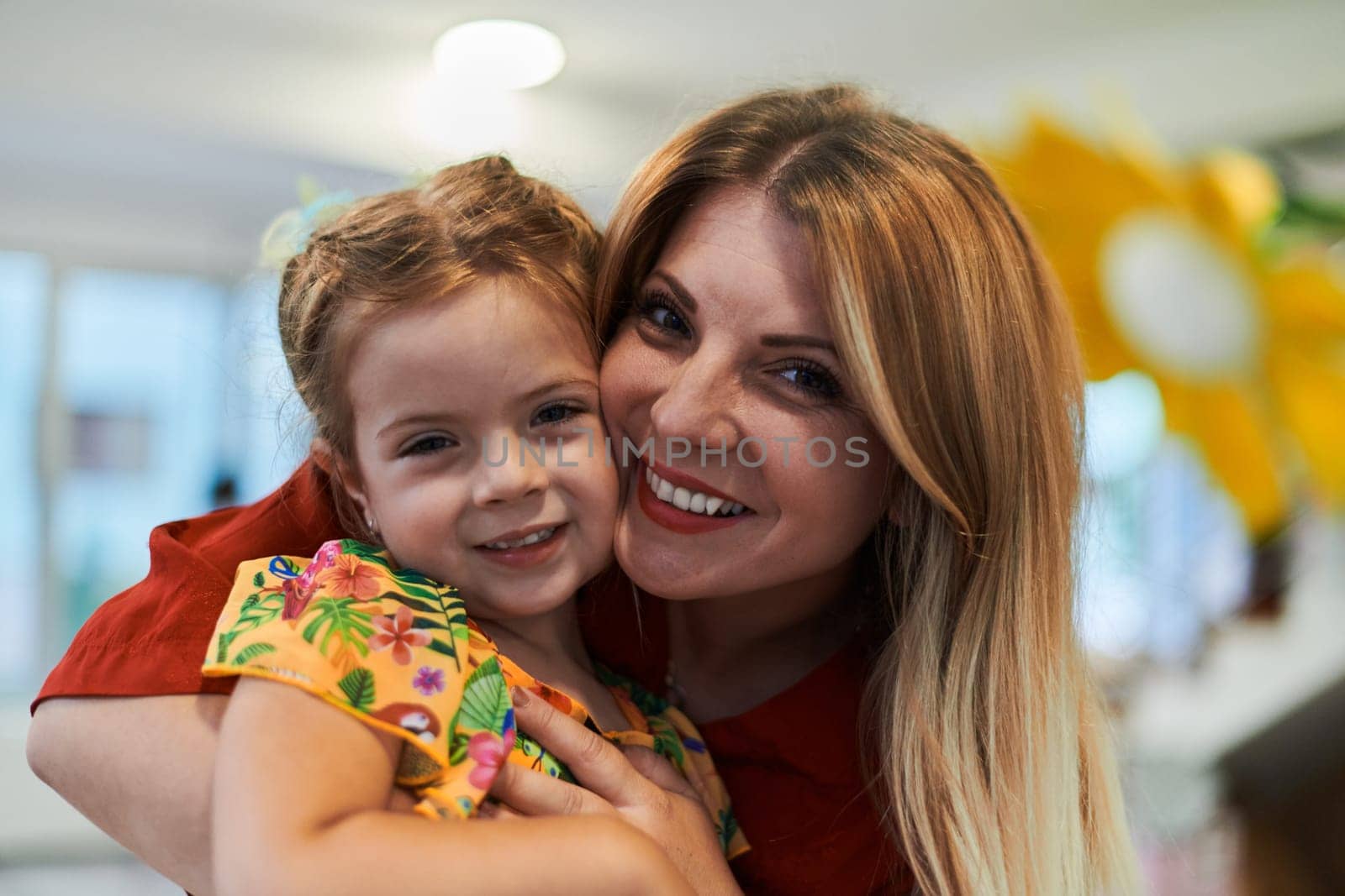 A cute little girl kissing and hugs her mother in preschool by dotshock