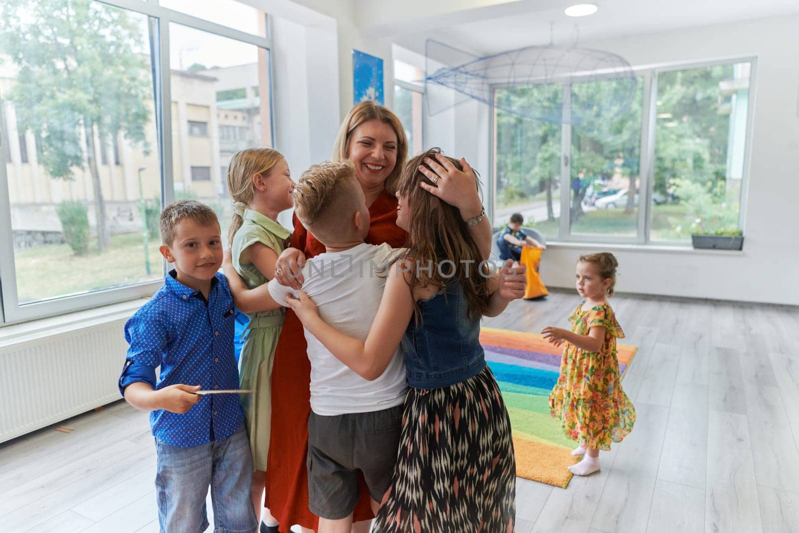 A child hugging a teacher in a modern kindergarten by dotshock
