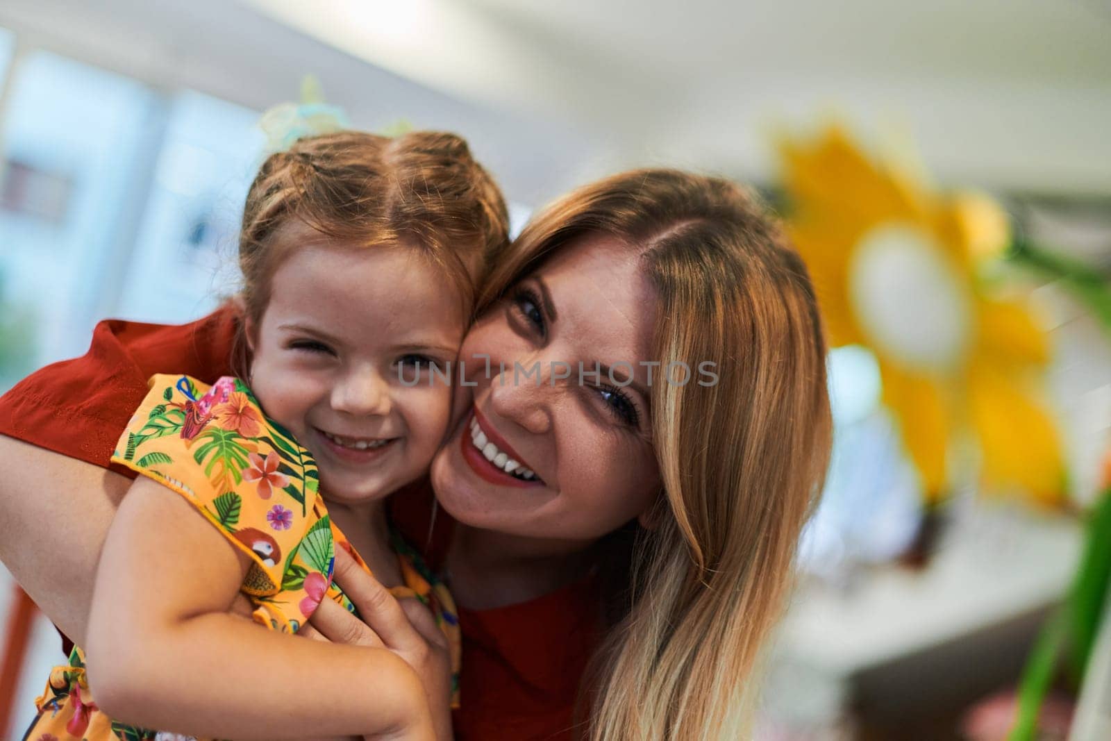 A cute little girl kissing and hugs her mother in preschool by dotshock