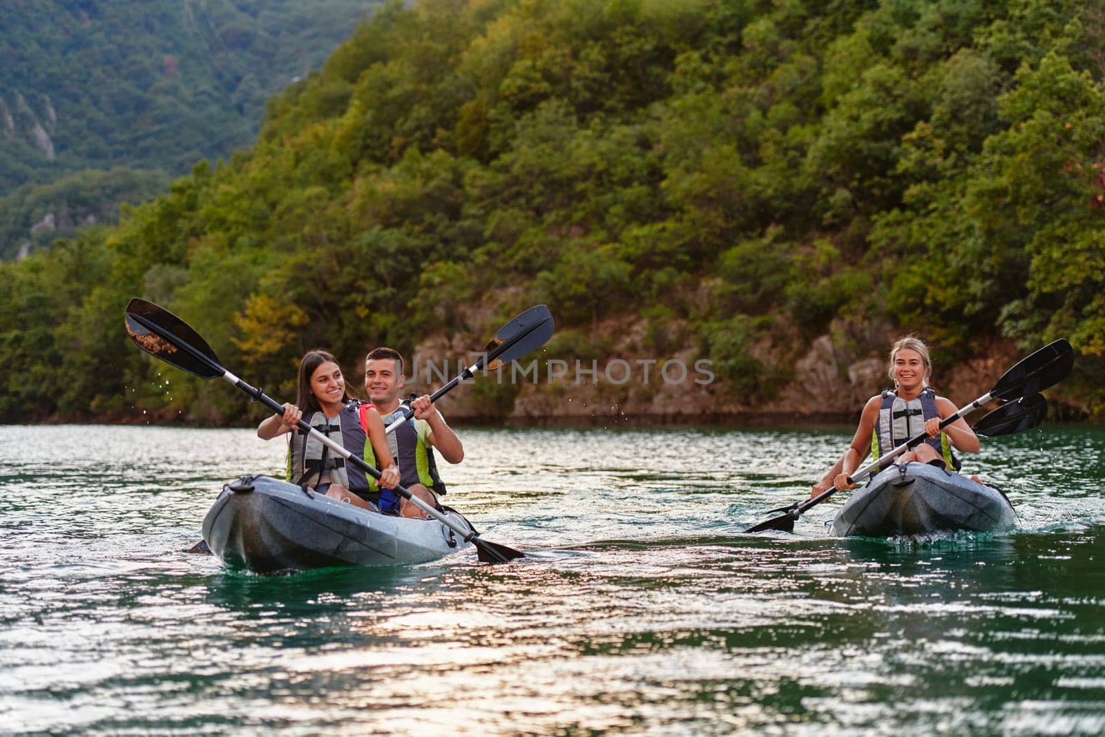 A group of friends enjoying fun and kayaking exploring the calm river, surrounding forest and large natural river canyons during an idyllic sunset