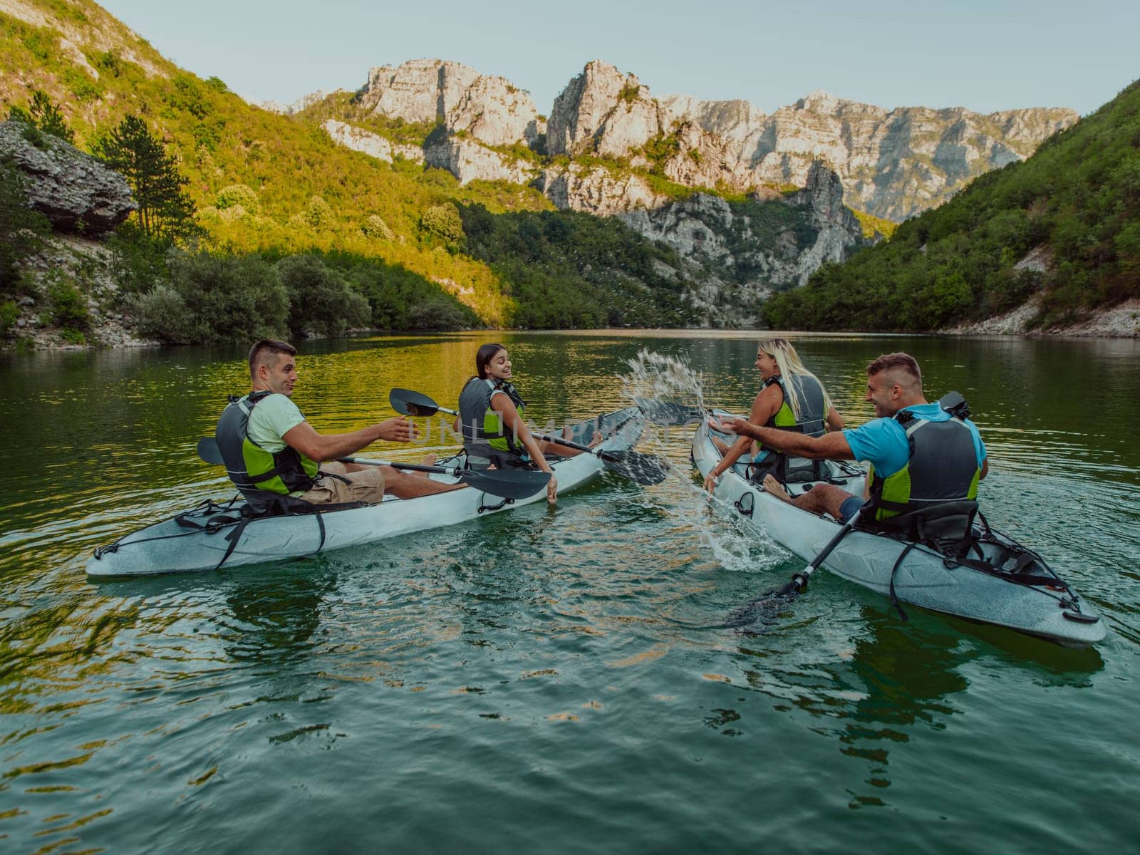 A group of friends enjoying having fun and kayaking while exploring the calm river, surrounding forest and large natural river canyons.