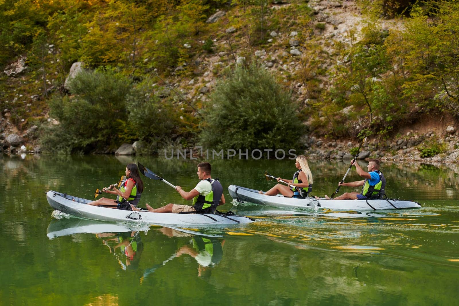 A group of friends enjoying having fun and kayaking while exploring the calm river, surrounding forest and large natural river canyons by dotshock