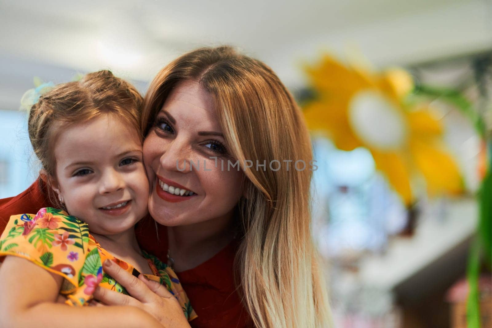 A cute little girl kissing and hugs her mother in preschool. High quality photo