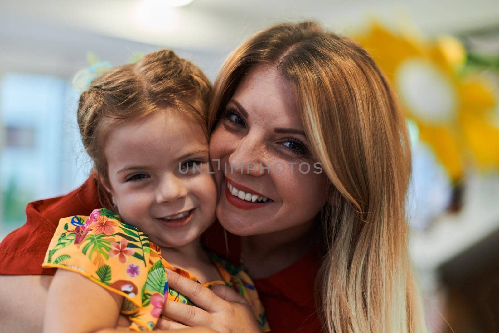 A cute little girl kissing and hugs her mother in preschool by dotshock