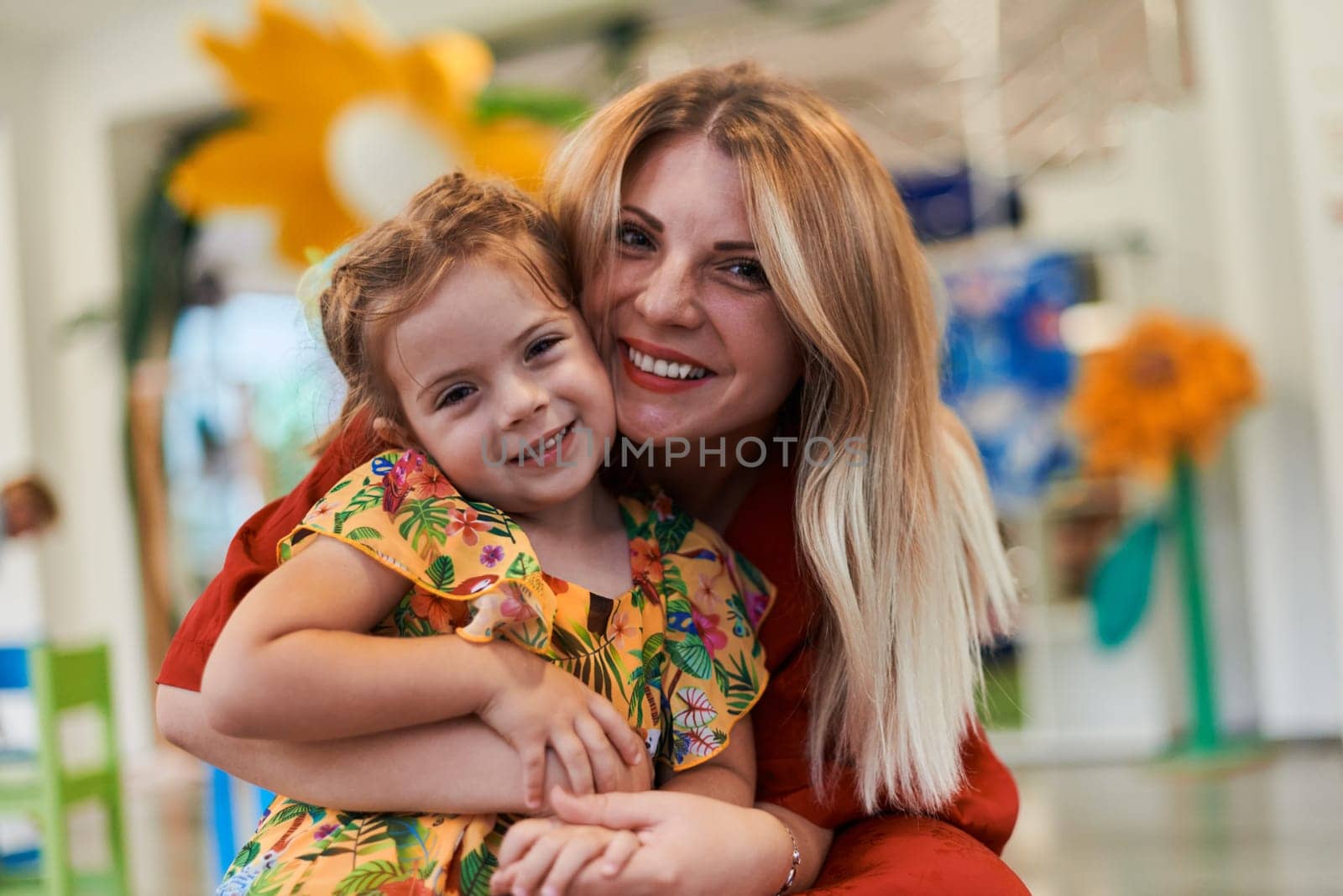 A cute little girl kissing and hugs her mother in preschool. High quality photo