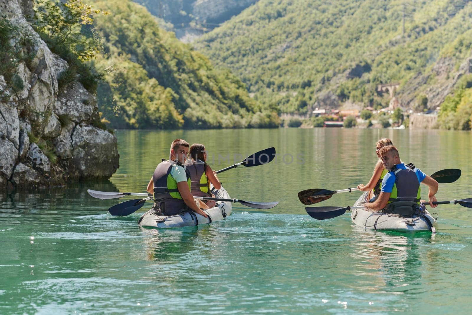 A group of friends enjoying having fun and kayaking while exploring the calm river, surrounding forest and large natural river canyons by dotshock