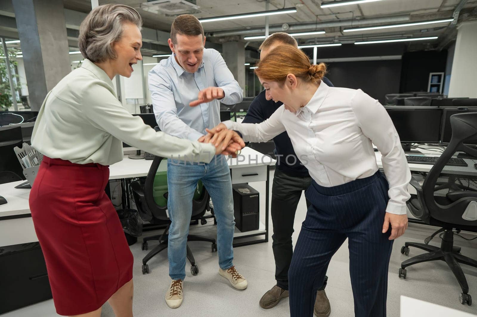 Four colleagues give the low five in the office