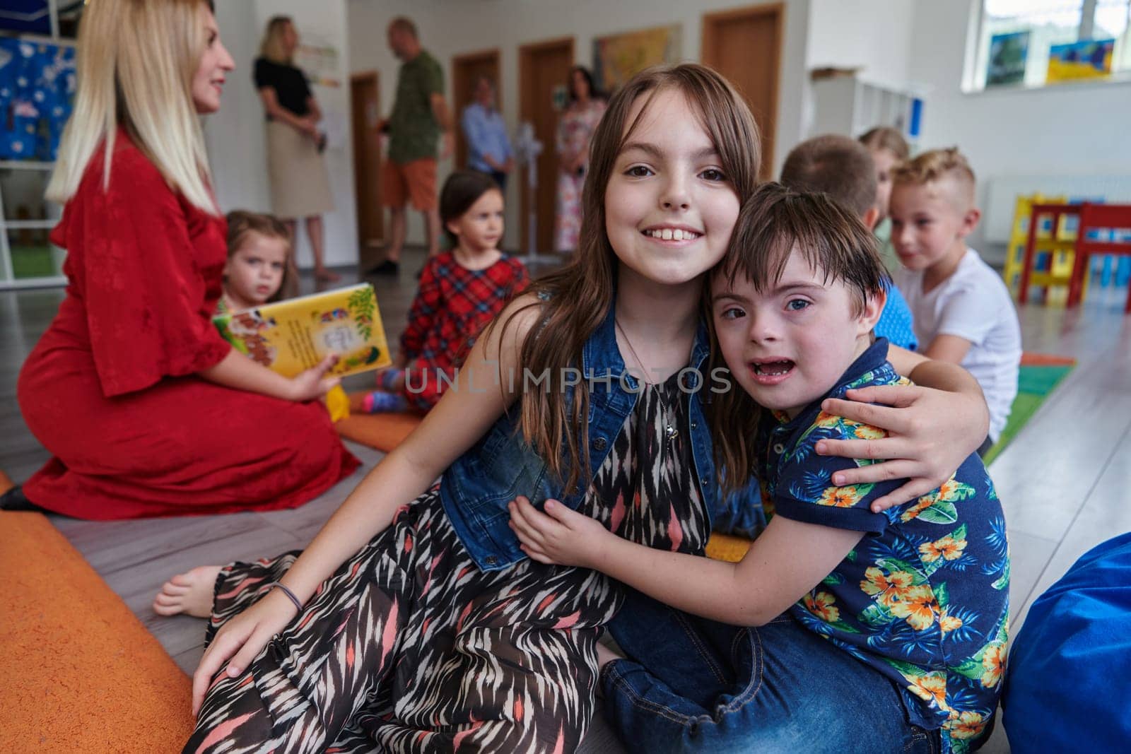 A girl and a boy with Down's syndrome in each other's arms spend time together in a preschool institution by dotshock