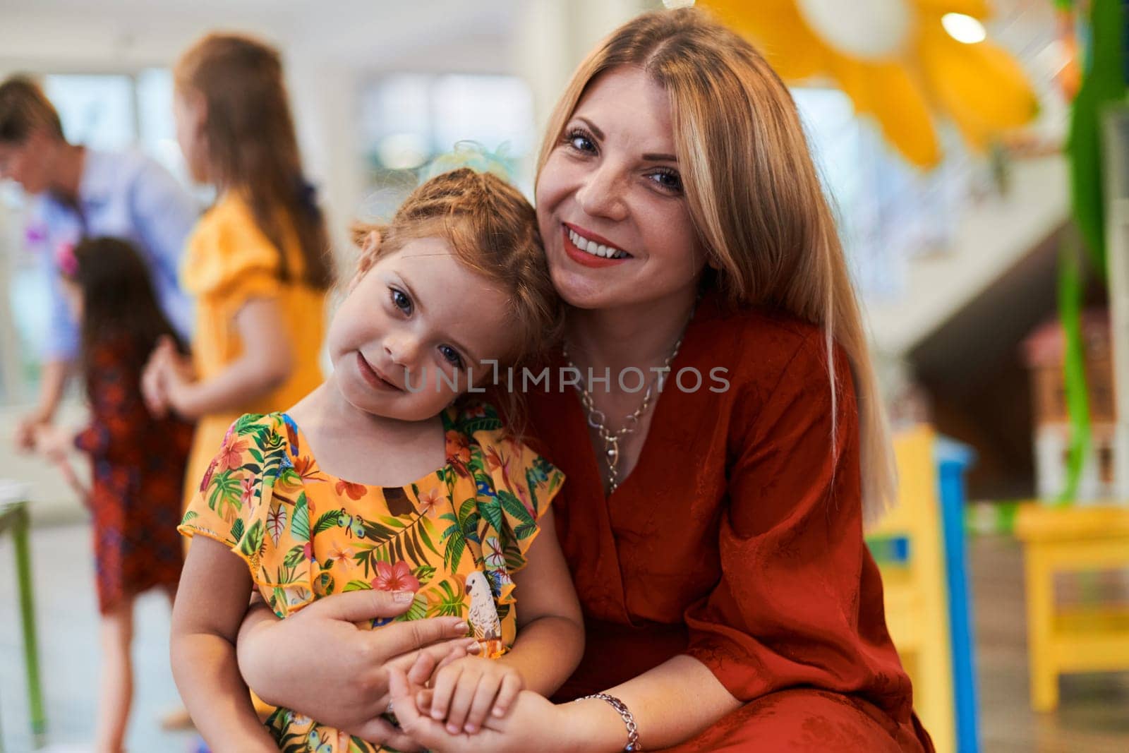 A cute little girl kissing and hugs her mother in preschool. High quality photo