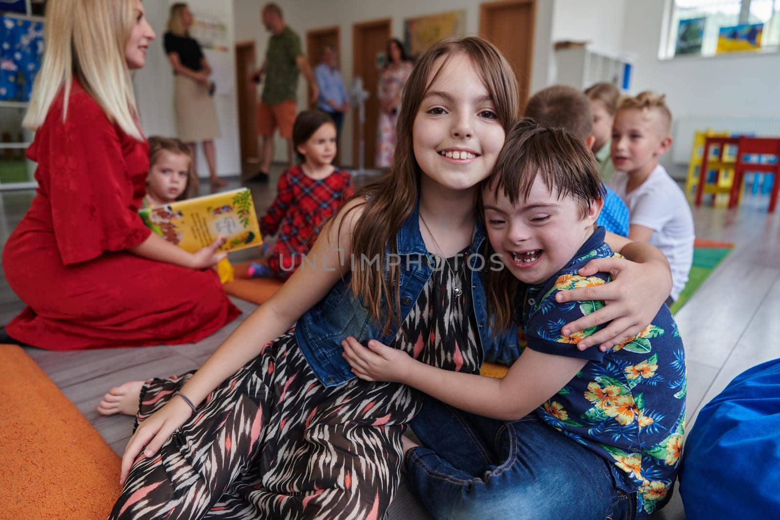 A girl and a boy with Down's syndrome in each other's arms spend time together in a preschool institution by dotshock
