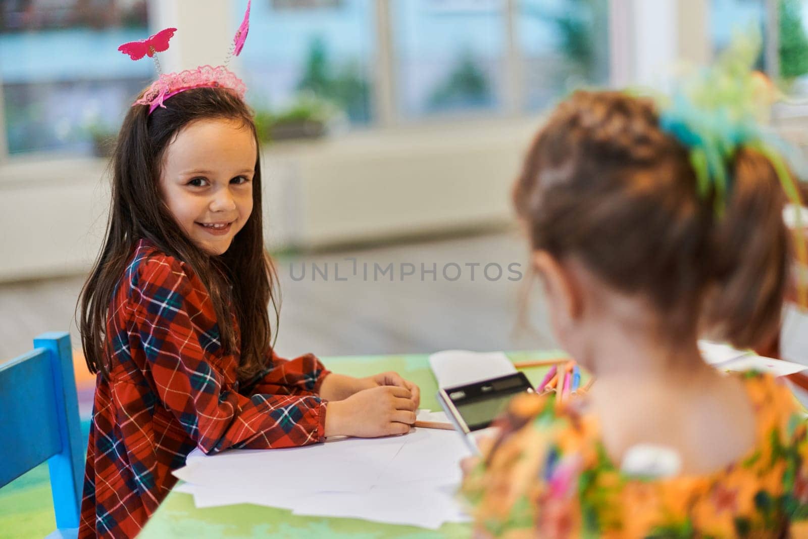 Creative kids during an art class in a daycare center or elementary school classroom drawing with female teacher