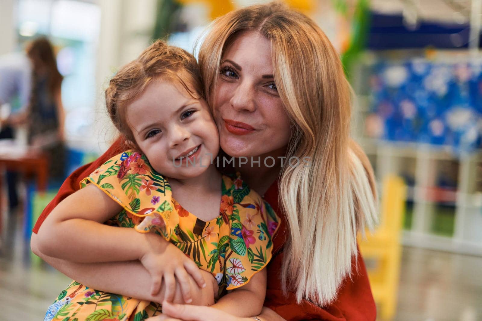 A cute little girl kissing and hugs her mother in preschool by dotshock