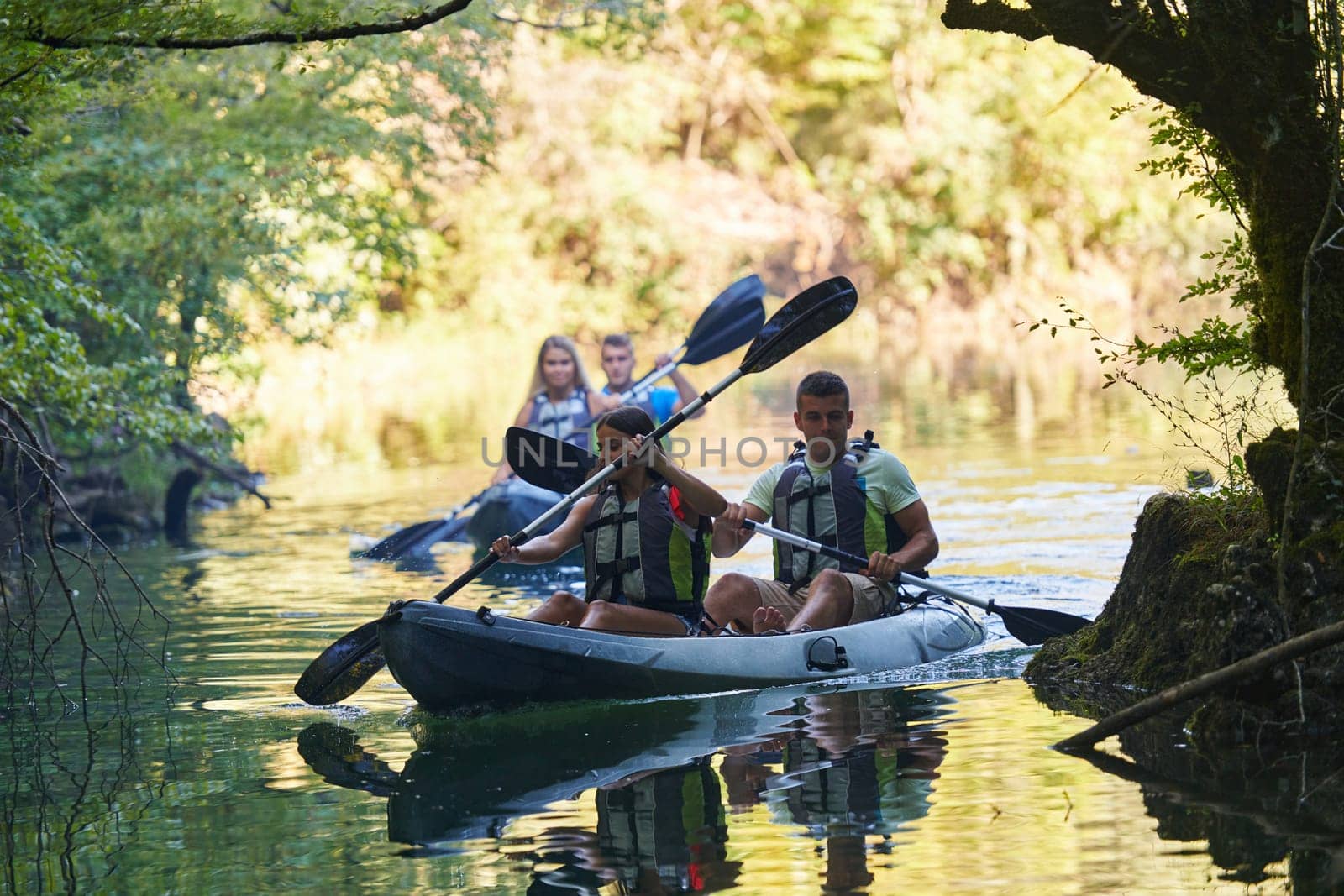 A group of friends enjoying having fun and kayaking while exploring the calm river, surrounding forest and large natural river canyons by dotshock