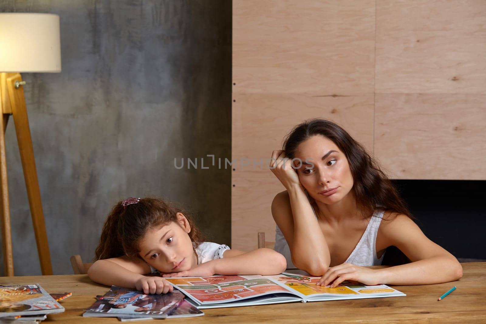 Portrait of a mother helping her small sweet and cute daughter to make her homework indoors. Happy family. by nazarovsergey