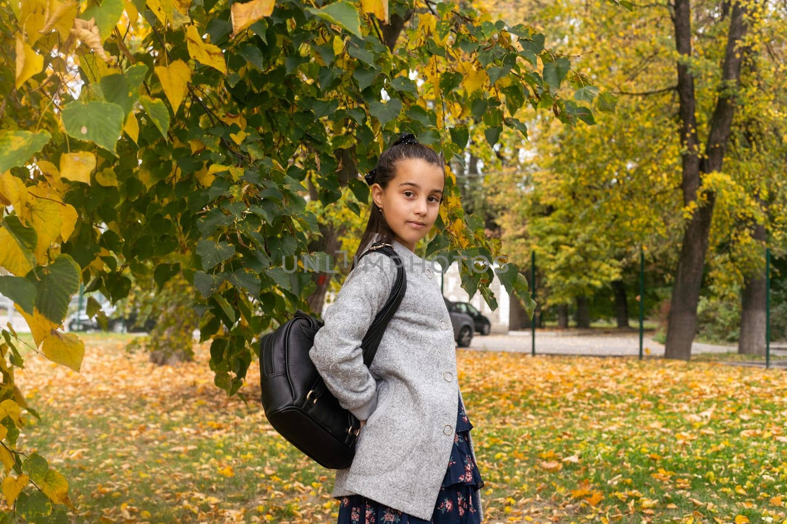 Cute young girl with a backpack heading to school on cold autumn morning. by Andelov13