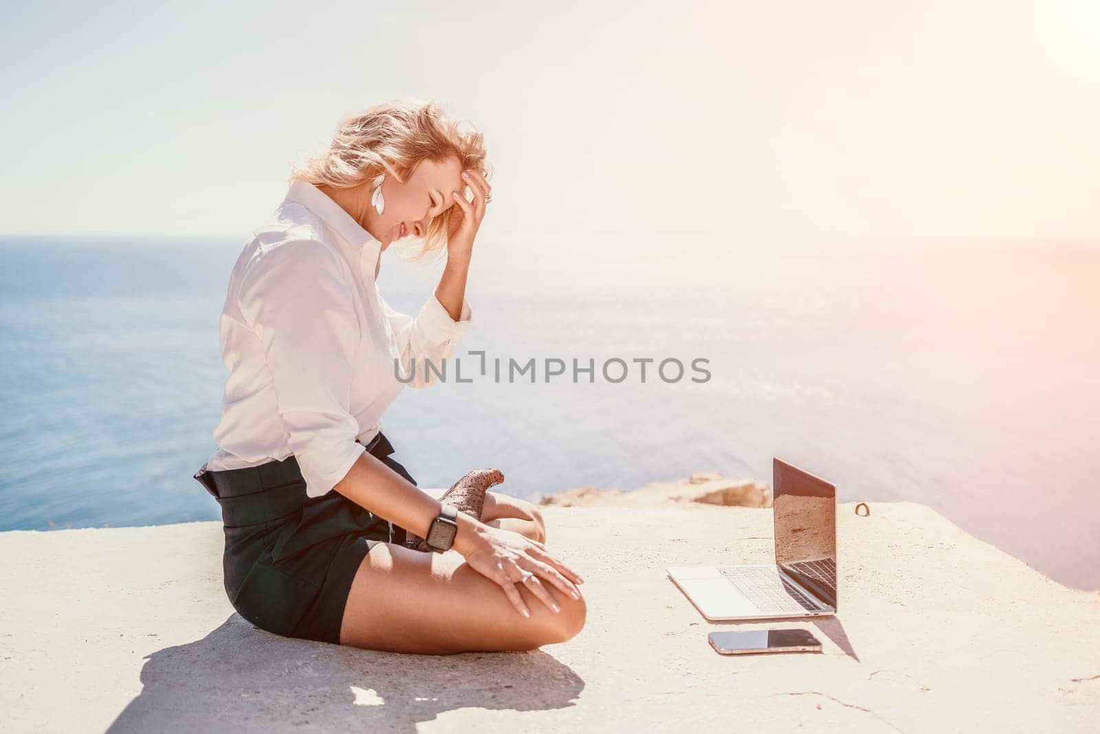 Happy girl doing yoga with laptop working at the beach. beautiful and calm business woman sitting with a laptop in a summer cafe in the lotus position meditating and relaxing. freelance girl remote work beach paradise