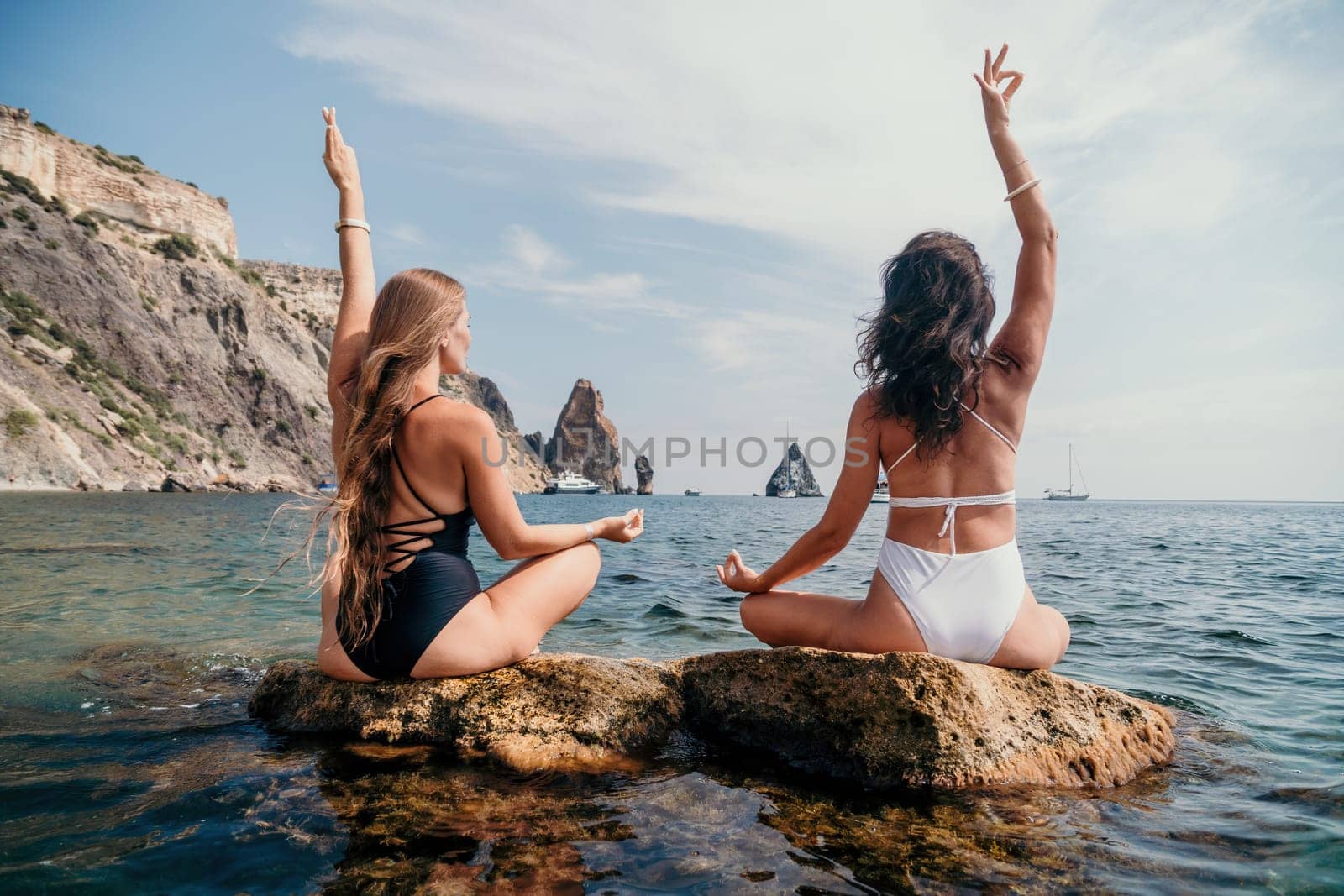 Woman sea yoga. Back view of free calm happy satisfied woman with long hair standing on top rock with yoga position against of sky by the sea. Healthy lifestyle outdoors in nature, fitness concept.