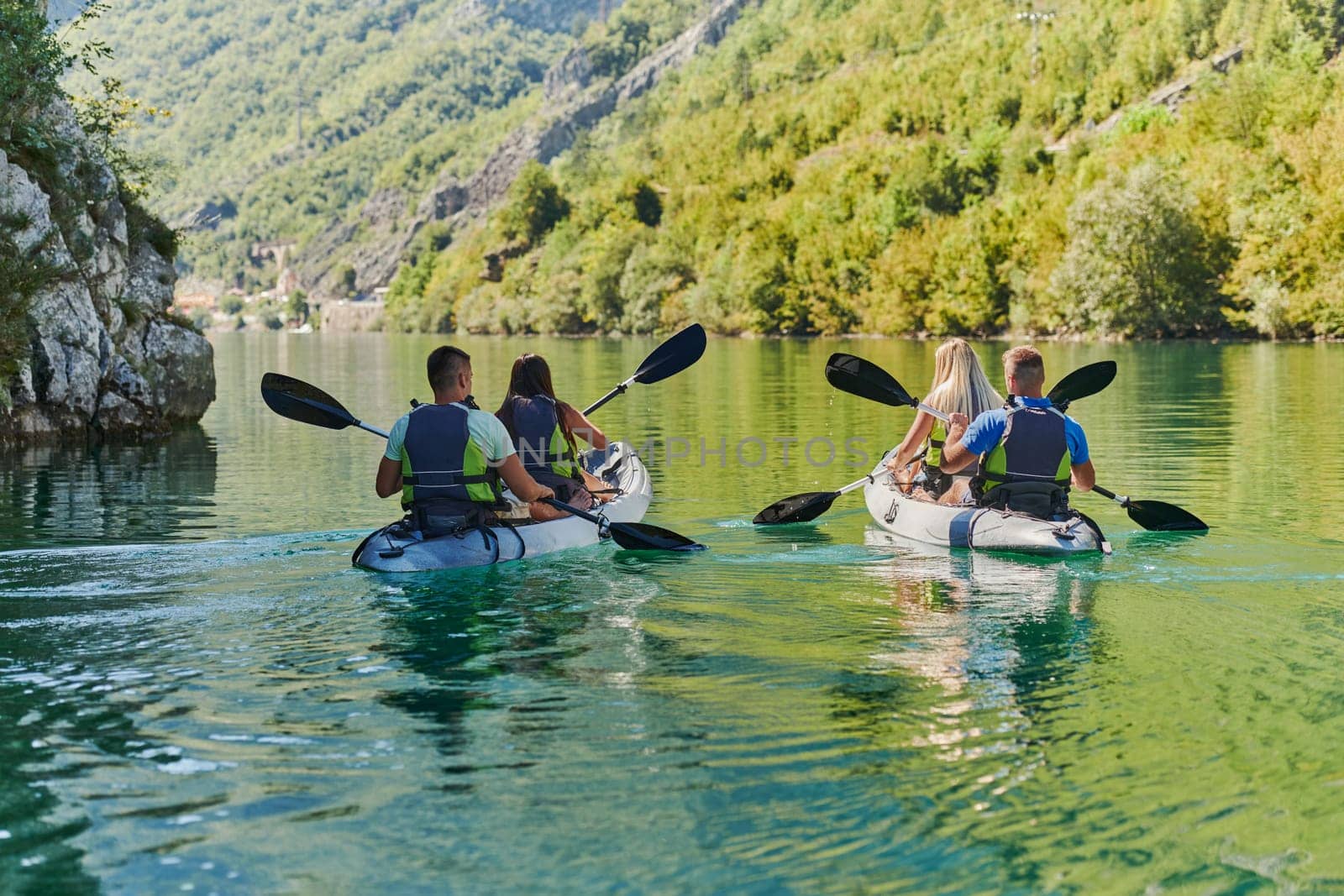 A group of friends enjoying having fun and kayaking while exploring the calm river, surrounding forest and large natural river canyons.