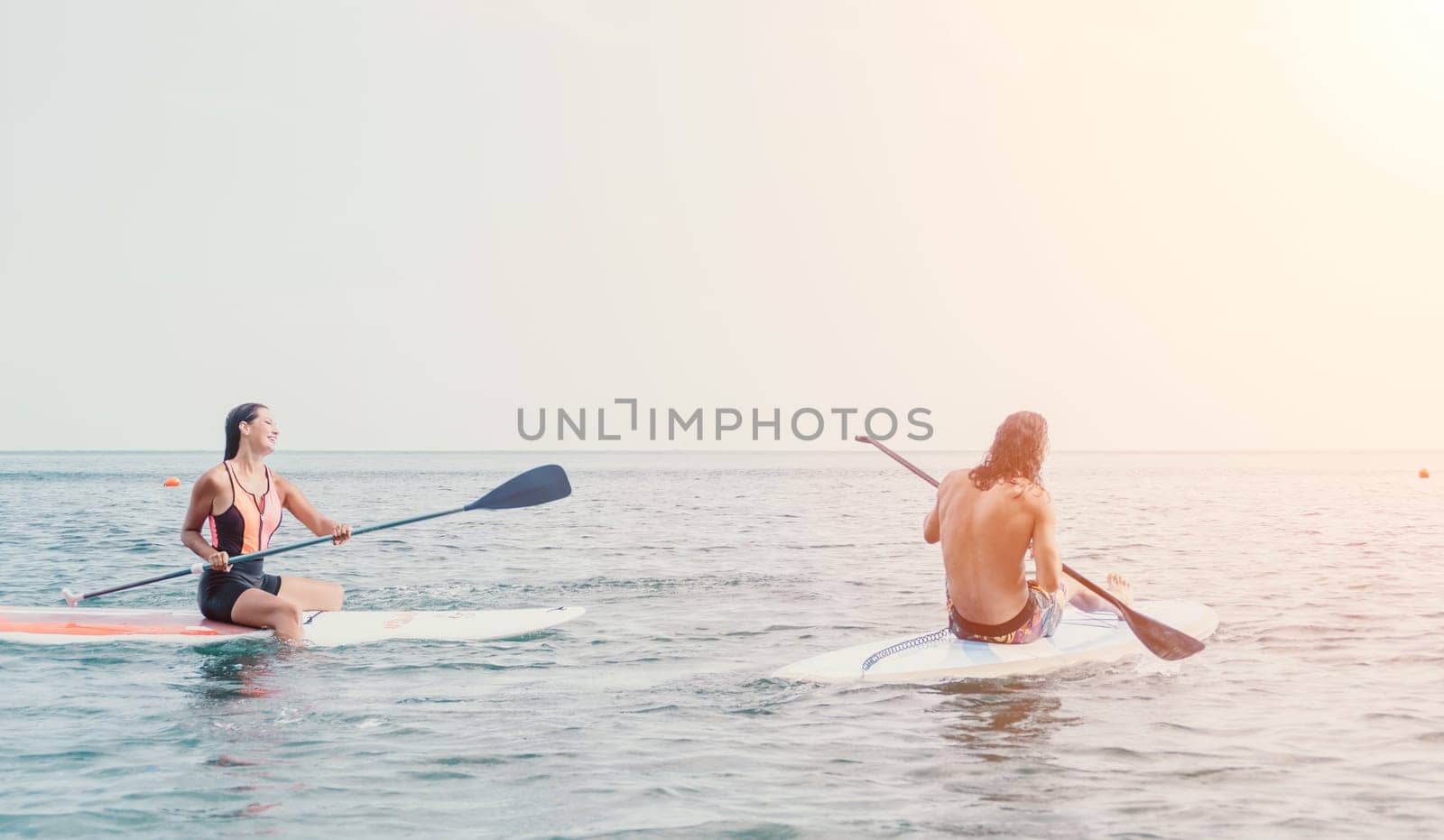 Woman sup yoga. Happy young sporty woman practising yoga pilates on paddle sup surfboard. Female stretching doing workout on sea water. Modern individual female outdoor summer sport activity