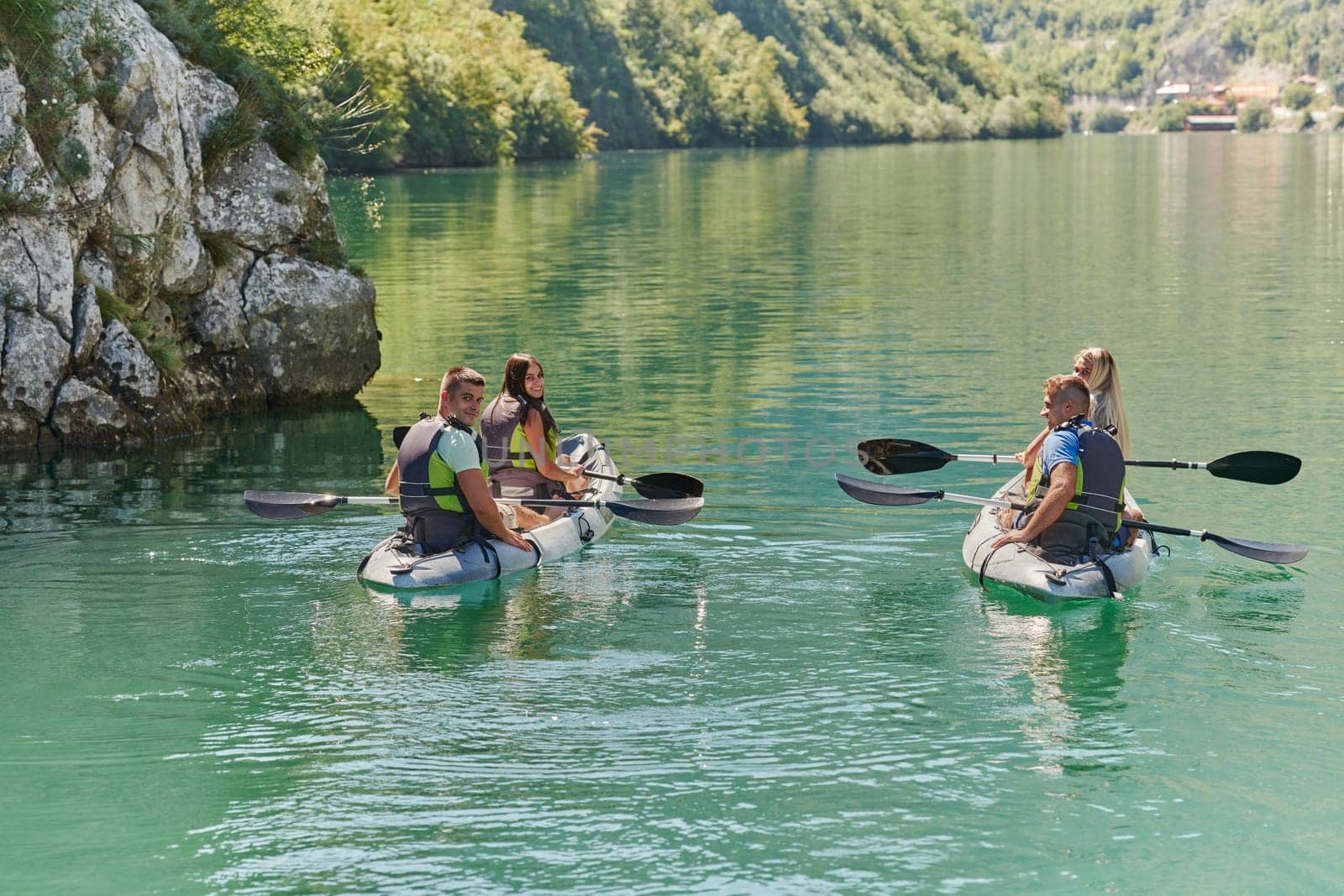 A group of friends enjoying having fun and kayaking while exploring the calm river, surrounding forest and large natural river canyons by dotshock