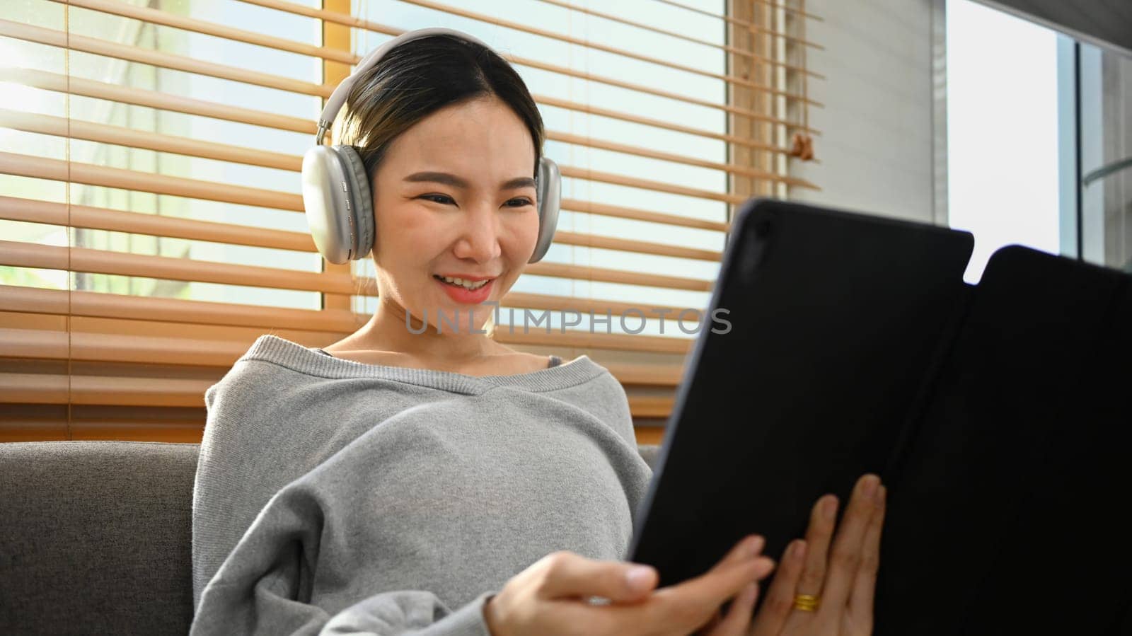 Joyful young asian woman wearing headphone and watching movie on digital tablet. Technology, people and lifestyle concept.