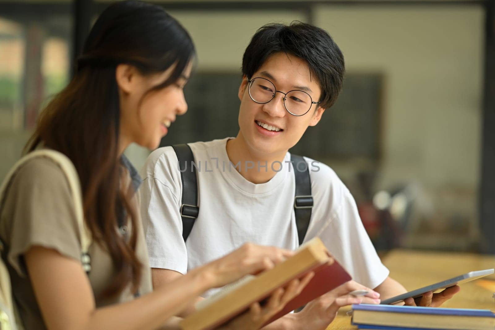 Two happy male and female university students collaborating on a project in campus. Education, Learning and technology concept.