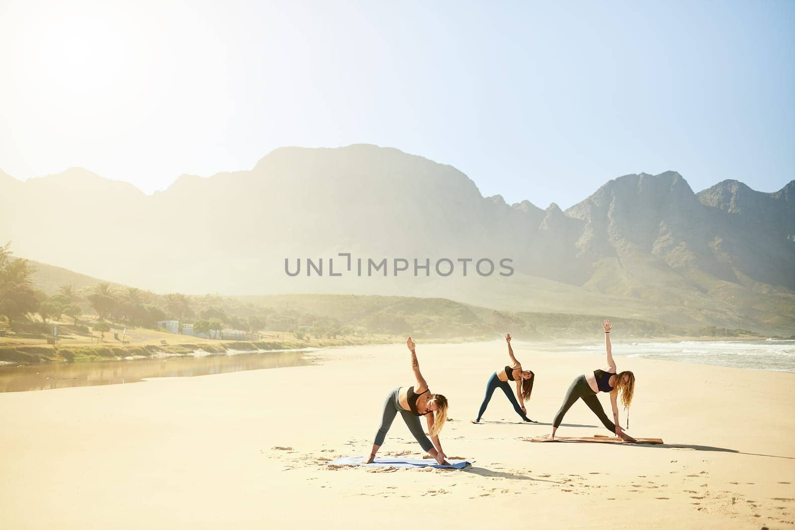 The practice of yoga is about gaining greater happiness and joy. three young women practicing yoga on the beach