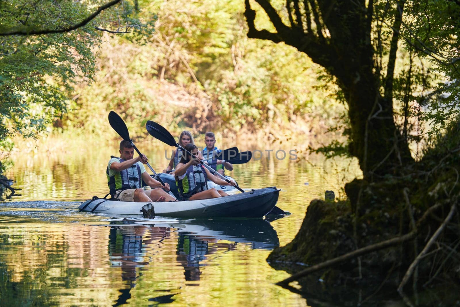 A group of friends enjoying having fun and kayaking while exploring the calm river, surrounding forest and large natural river canyons.