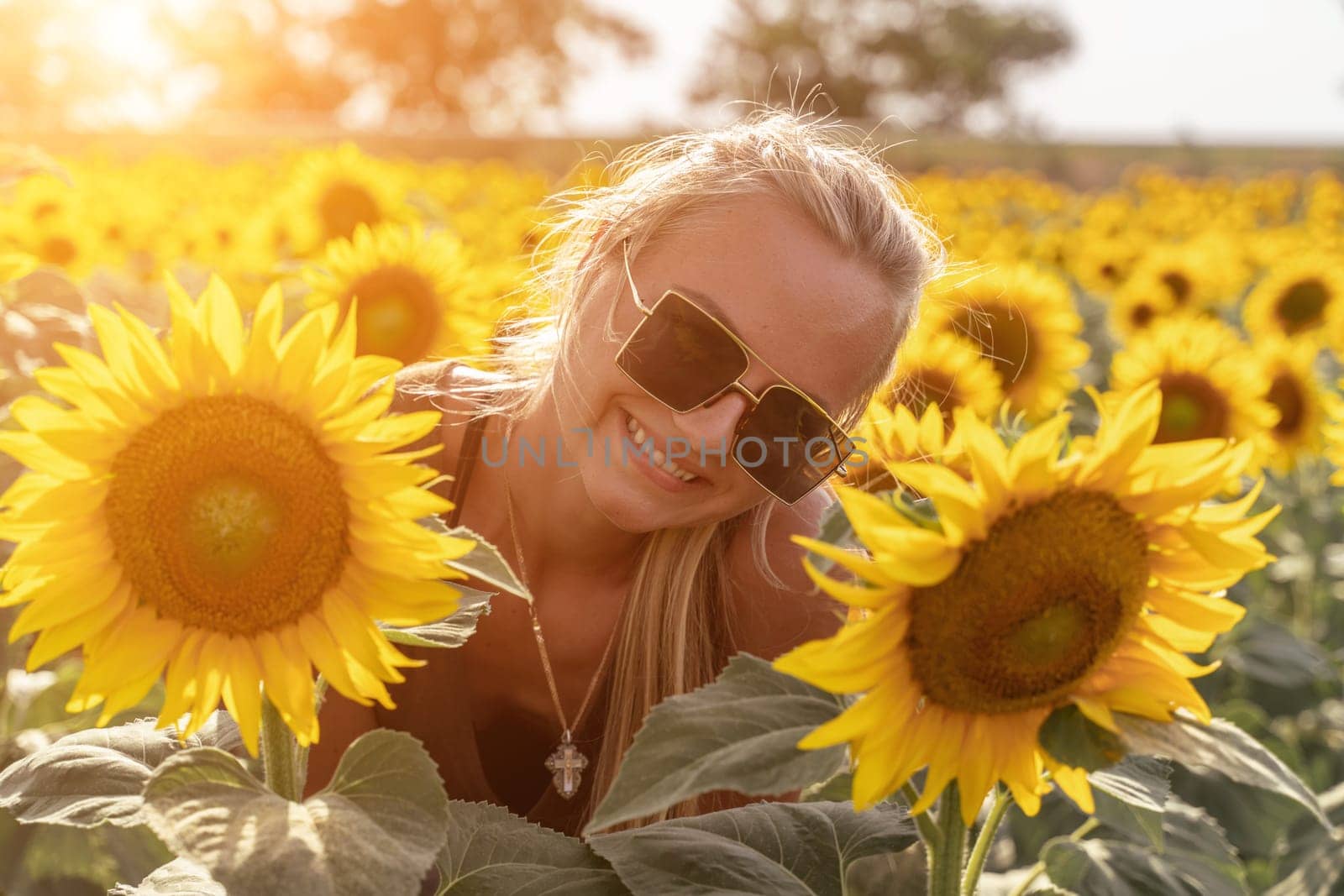 Beautiful woman in sunflower field at sunset enjoying summer nature. Attractive blonde with long healthy hair