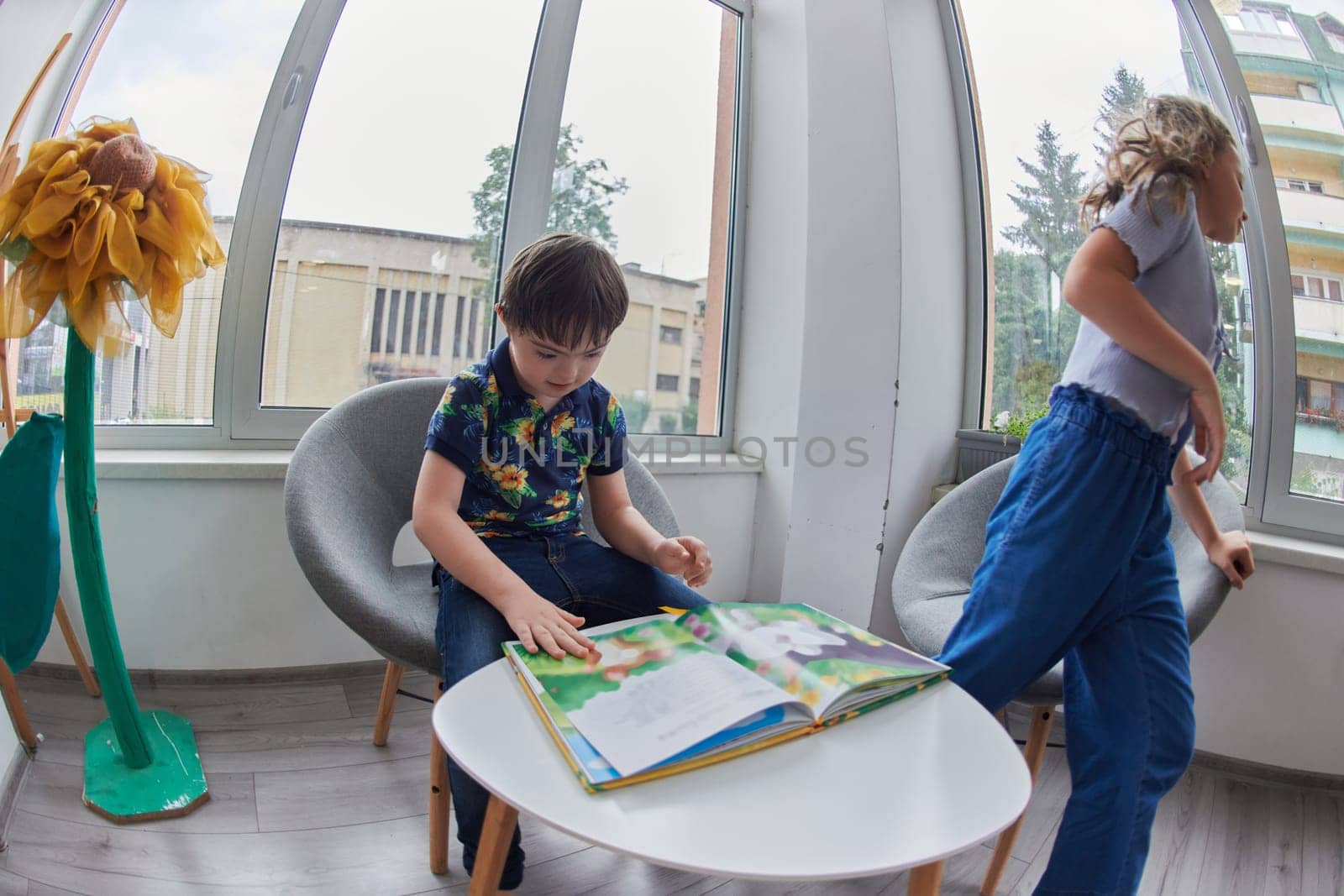 Creative kids during an art class in a daycare center or elementary school classroom drawing and reading book by dotshock