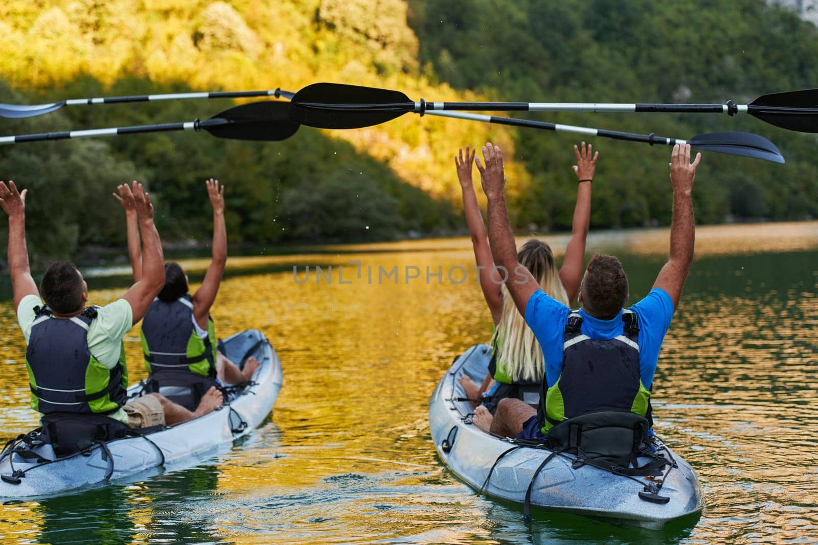 A group of friends enjoying having fun and kayaking while exploring the calm river, surrounding forest and large natural river canyons.